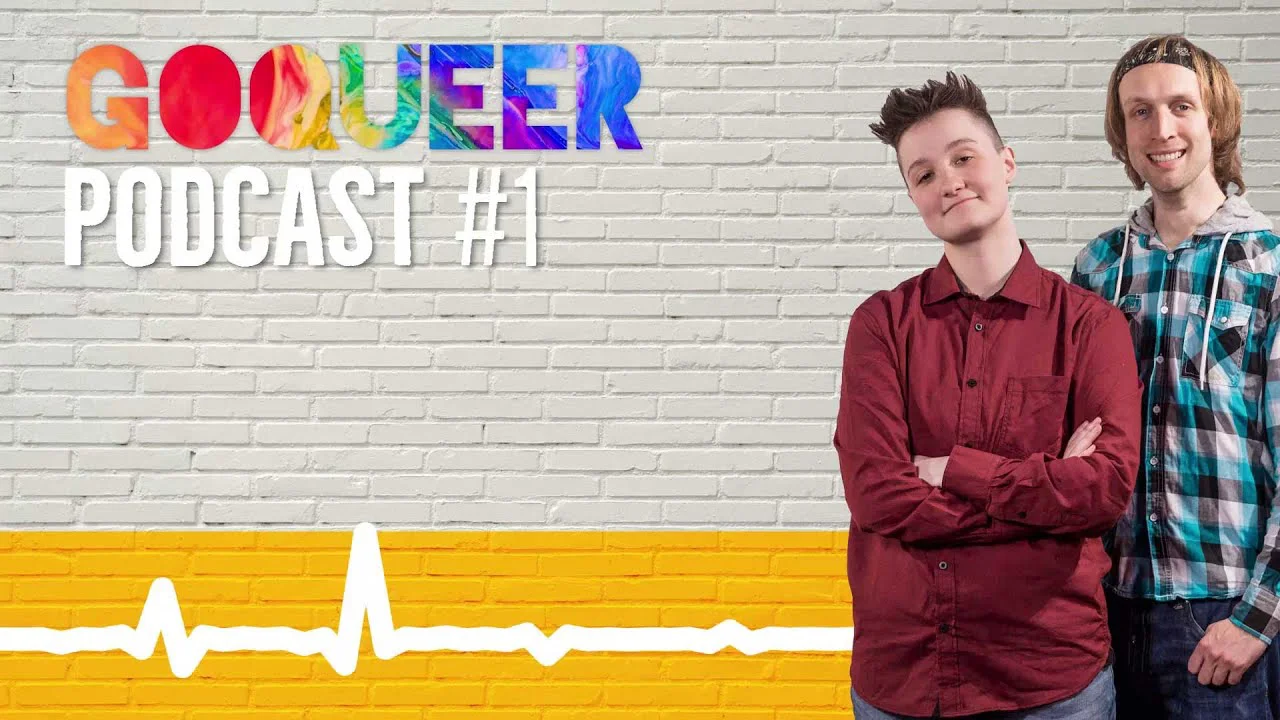 Zwei junge Menschen stehen vor einer weißen Ziegelwand mit buntem "GOQUEER PODCAST #1" Schriftzug und gelbem Audiostreifen.