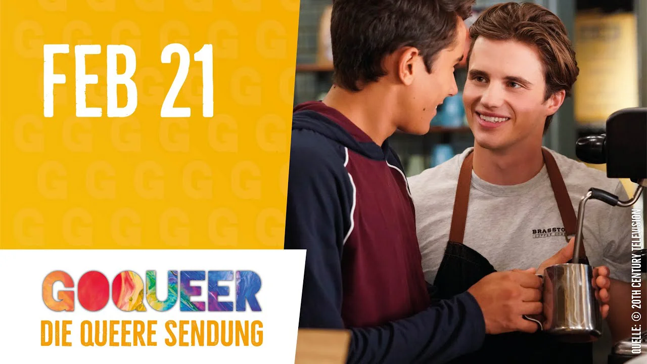 Zwei junge Männer lächeln sich in einem Café an, links gelbe Grafik mit "FEB 21" und GOQUEER-Logo.