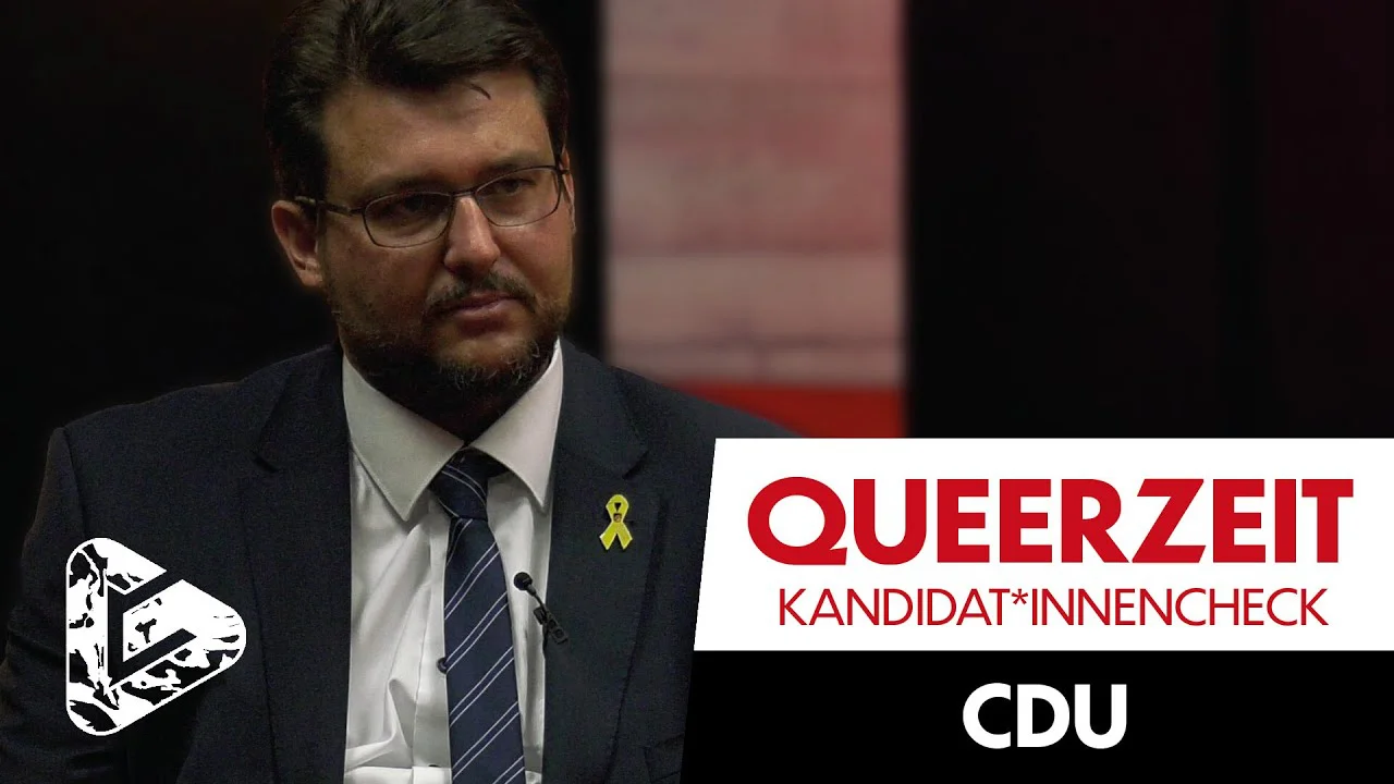 Mann im Anzug mit gelber Schleife vor Logo "QUEERZEIT KANDIDAT*INNENCHECK CDU