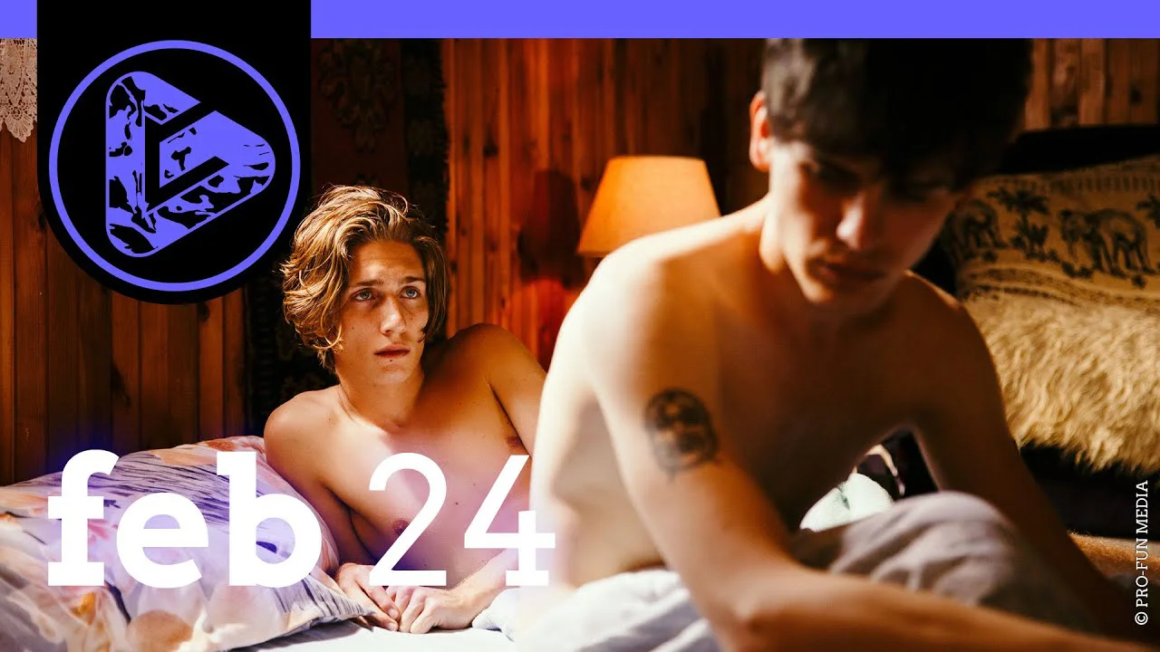 Zwei Personen liegen im Bett, eine schaut zur Kamera, die andere ist unscharf im Vordergrund, Text "feb24" eingeblendet.