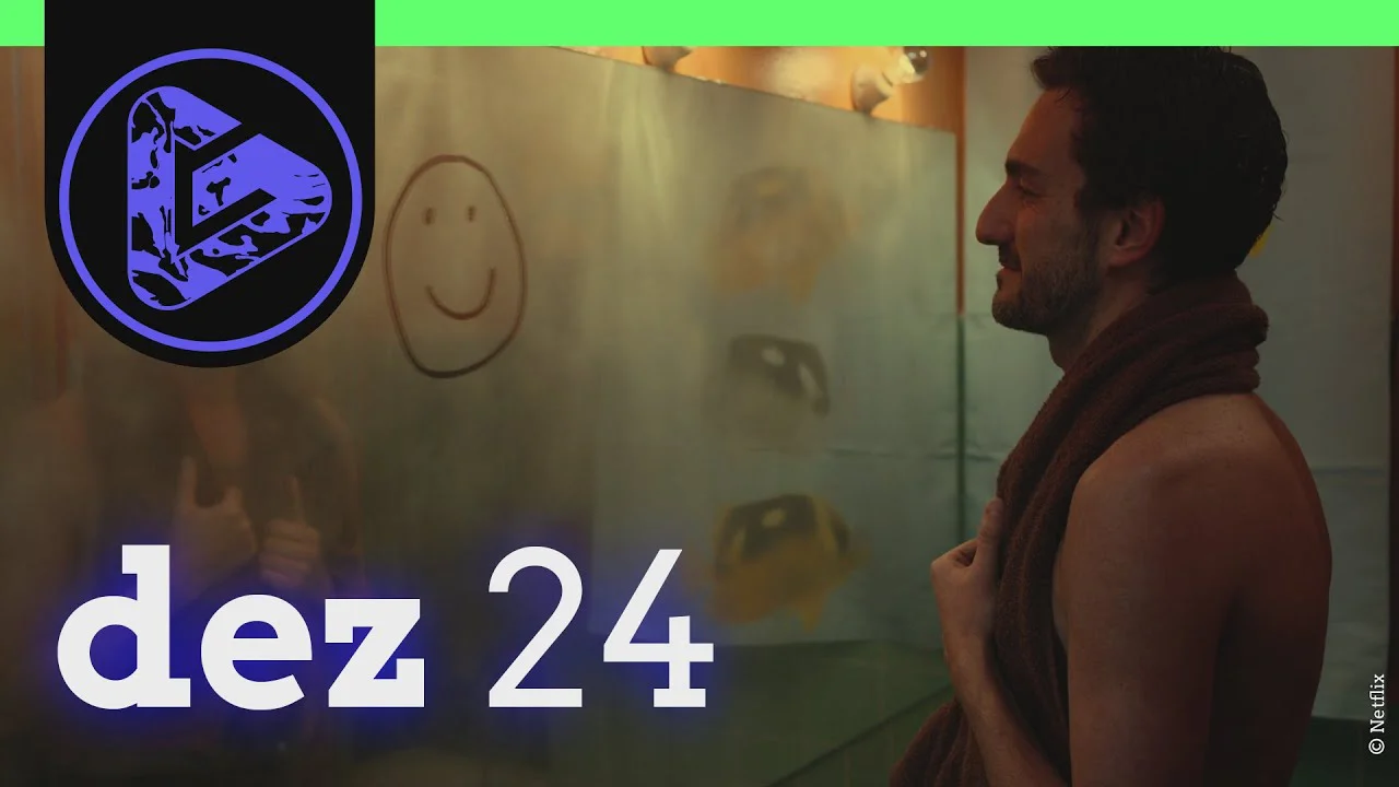 Mann lächelt vor einer Glasscheibe mit Zeichnungen, links ein Logo, unten der Text "dez 24".