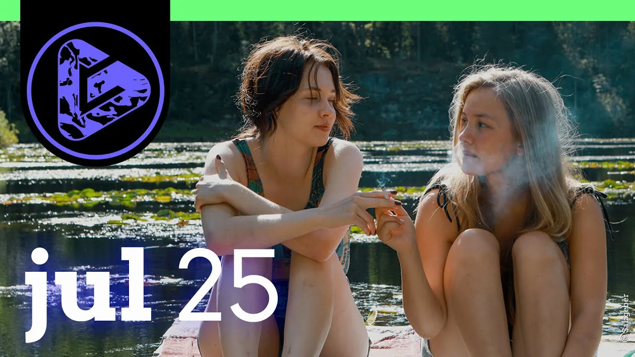 Zwei Frauen sitzen am Wasser, eine raucht, im Hintergrund ein See mit Steg, Datum "jul25" eingeblendet.